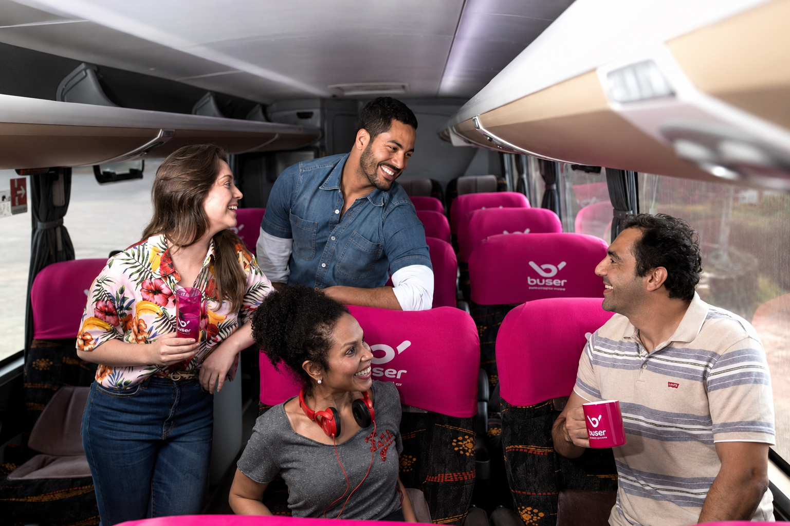 Quatro pessoas sorrindo dentro do ônibus da Buser durante uma viagem